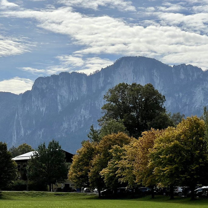 the European Alps in Austria, with snow-capped peaks towering over a lush green valley.