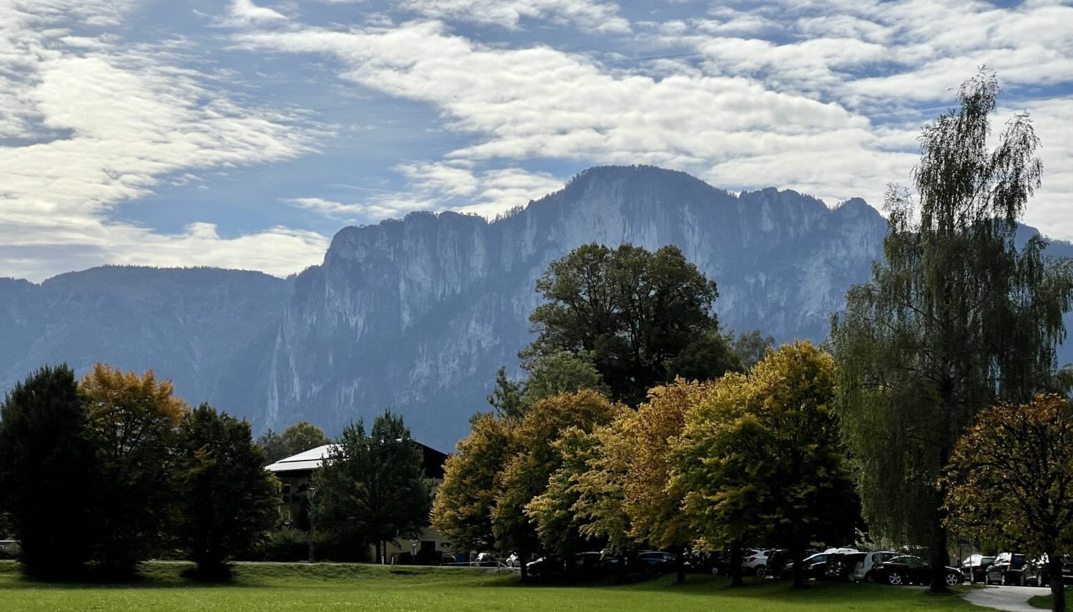 the European Alps in Austria, with snow-capped peaks towering over a lush green valley.