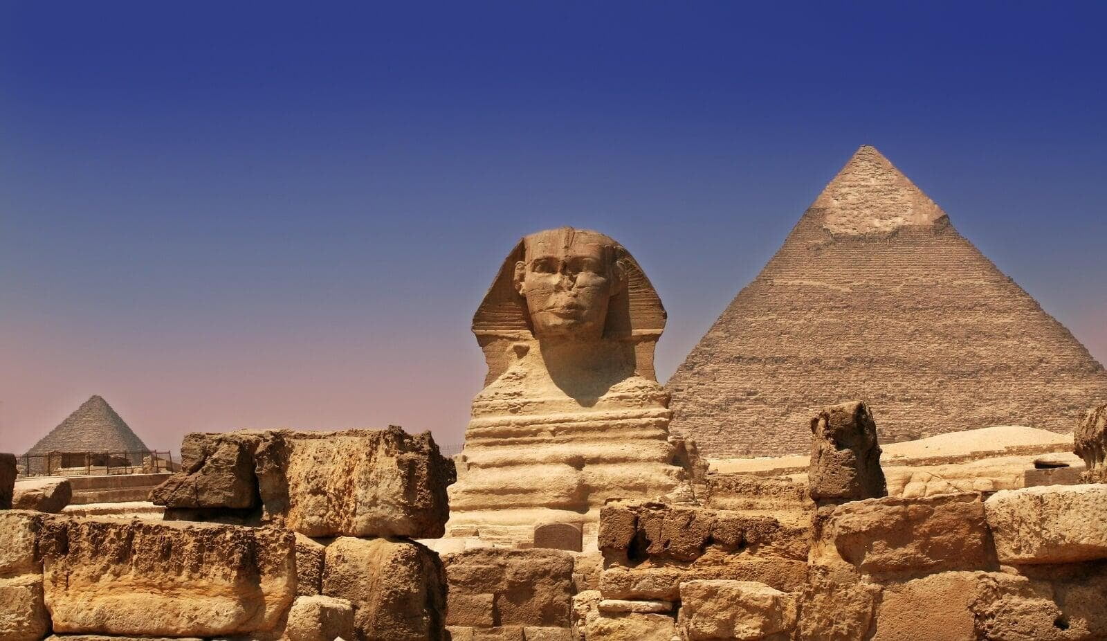 the Sphinx and the Pyramids of Giza in Egypt, with the ancient structures set against a clear, bright sky