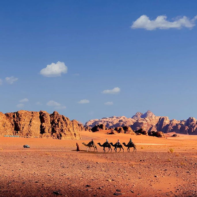 the Wadi Rum desert in Jordan, with vast sandy plains and towering rock formations under a clear blue sky