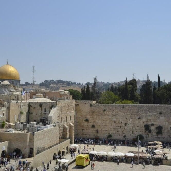 the Western Wall and Temple Mount in Jerusalem, with the Dome of the Rock visible in the background under a clear sky