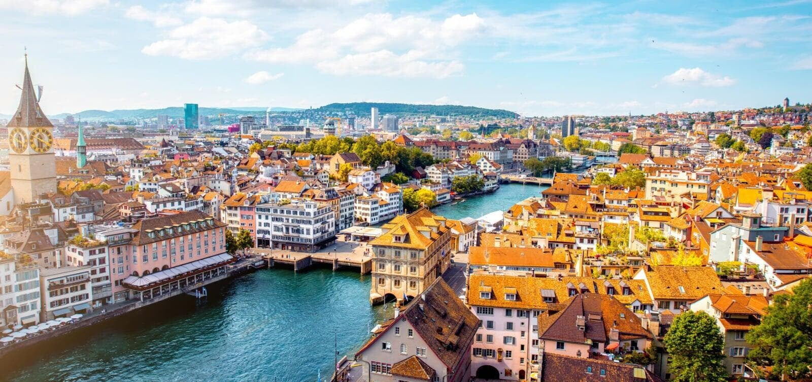 a scenic view of Zurich, Switzerland, with the cityscape and a prominent church steeple visible against a clear sky