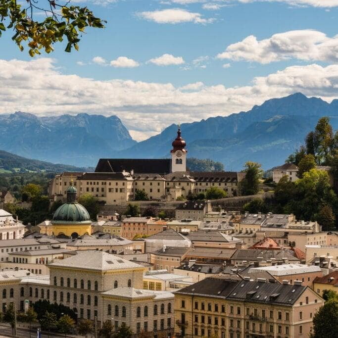 Salzburg, Austria, with its historic buildings and scenic landscape set against a backdrop of rolling hills and a clear sky