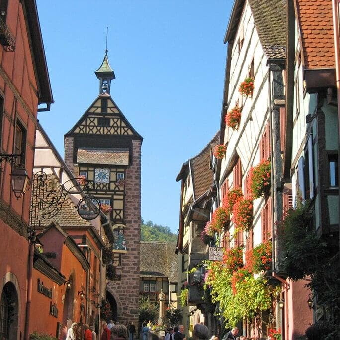 the picturesque village of Riquewihr, France, with its charming half-timbered houses and cobblestone streets under a bright, clear sky