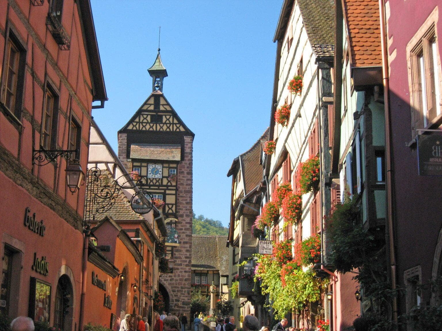 the picturesque village of Riquewihr, France, with its charming half-timbered houses and cobblestone streets under a bright, clear sky